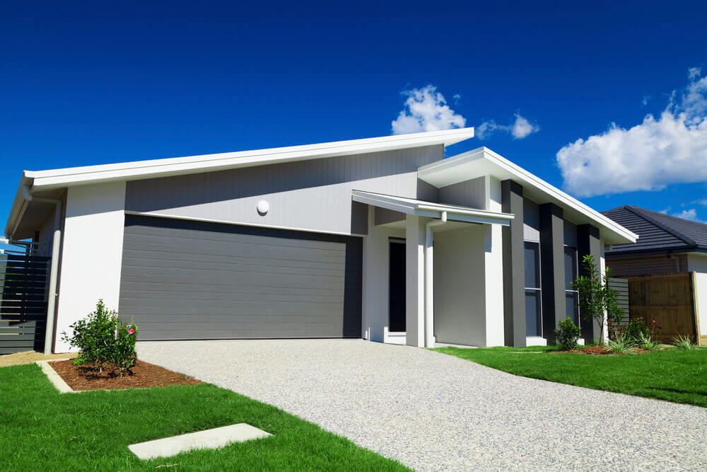 view of the front of a suburban house with green grass and a new concrete driveway poured by concreting Ipswich