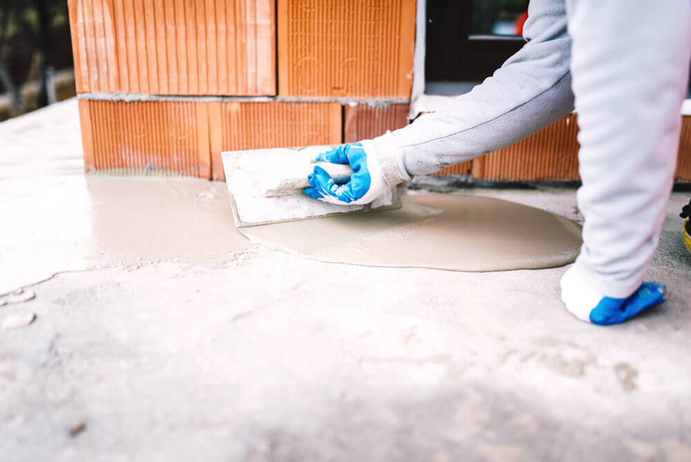view of a concrete resurfacing worker's hand holding a trowel surrounded by resurfacing liquid