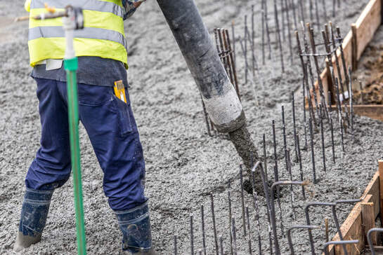 A concreting Ipswich worker guiding a concrete pump hose while standing in wet concrete