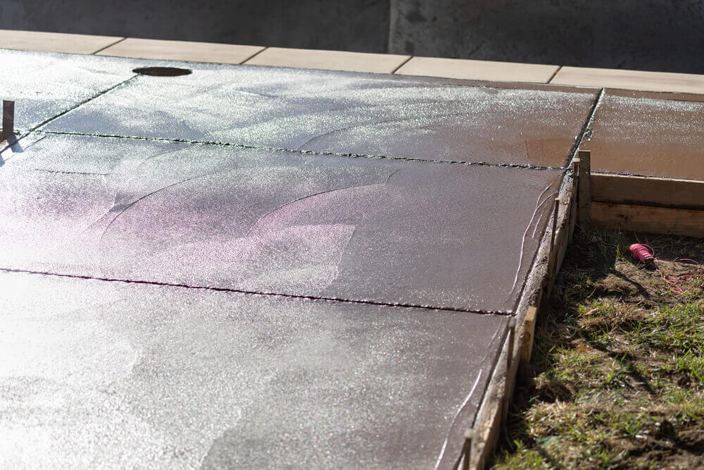 image of a freshly poured concrete driveway with the sun reflecting of the wet surface