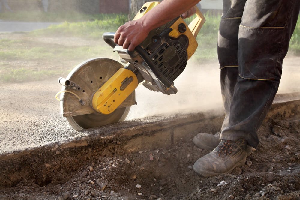 a worker using a Concrete Cutting machine on the edge of a house slab